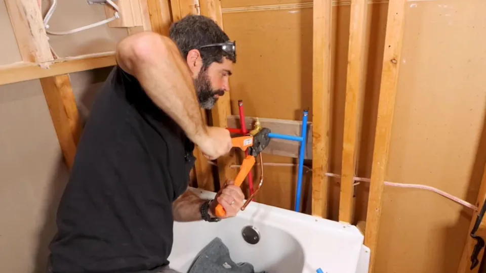 Plumber working on a tub drain and supply behind an open wall, Shower and Bathtub Installation in Downey, CA
